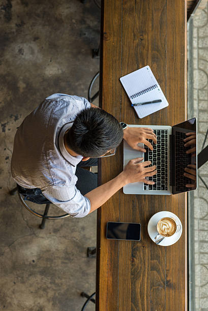 Asian student chatting with online friends on laptop stock photo