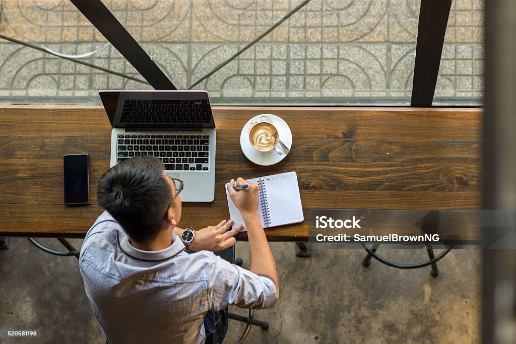 Hombre de negocios joven asiática tomar nota junto a computadora portátil sobre una mesa de madera - Foto de stock de Café bar libre de derechos