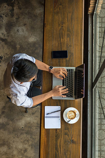 istock Young businessman using laptop with smartphone and coffee beside 520581422