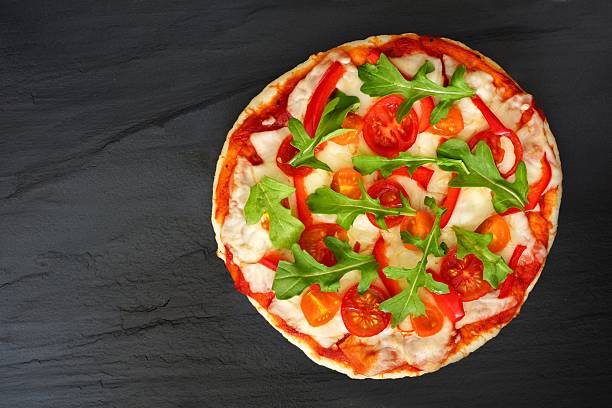 istock Homemade pizza with arugula and tomatoes against slate 520583502