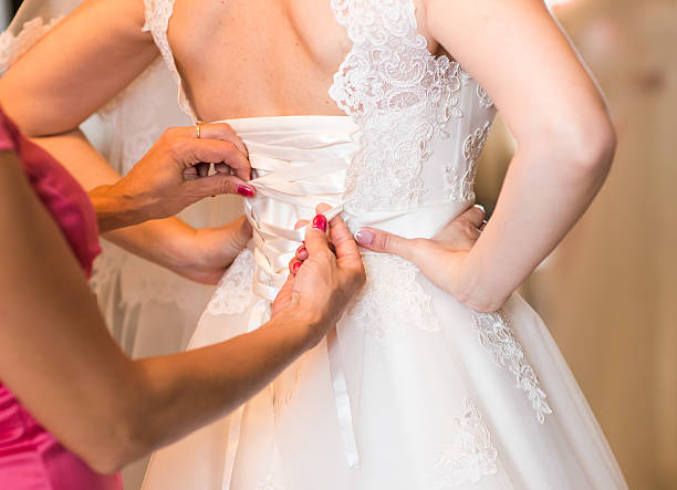 istock bridesmaids helping bride lacing up dress 520585138