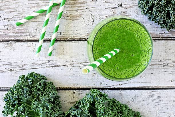 istock Green kale smoothie with straw overhead view on old wood 520585734