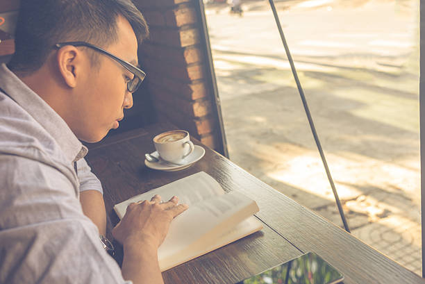istock Asian man enjoying a beautiful day with book and coffee 520586062