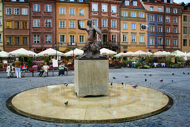 Warsaw, Poland - August 28, 2008: Unidentified people sit on benches at Old Town Market Place with the Mermaid of Warsaw monument - a symbol of Warsaw.