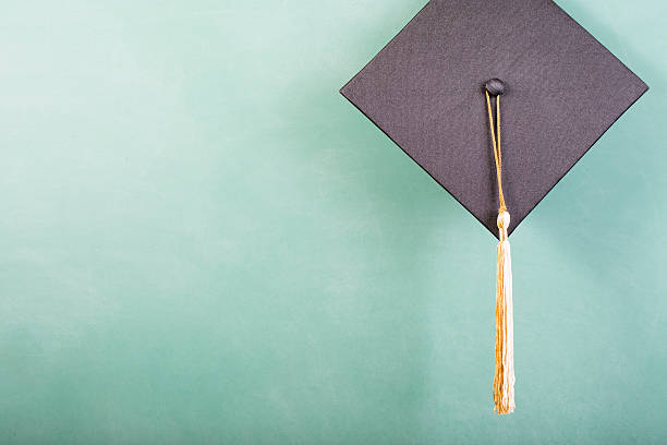A young woman in a Red Graduation gown holding her cap and tassel at her side