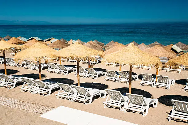 Beach sun loungers by the Mediterranean Sea. Chaise-longues on the beach. Sunbed and umbrella on beach