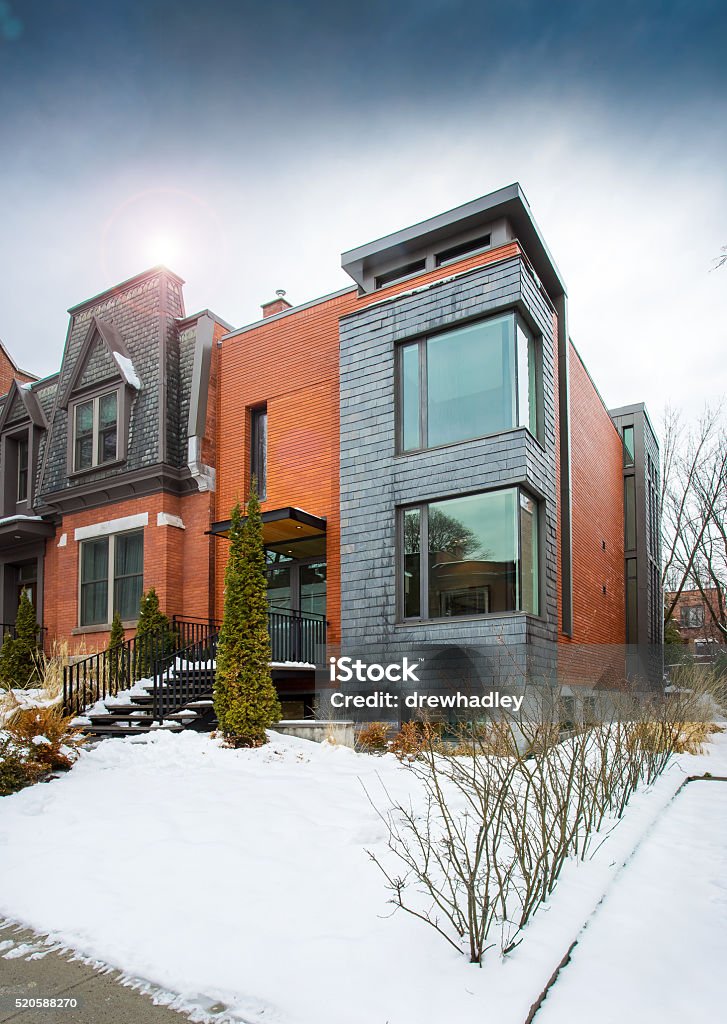 Exterior of contemporary style townhouse in winter. A vertical image of the exterior of a contemporary style townhouse in winter, with sun flare and snow on the ground. Seen from the street. Space for copy. House Stock Photo