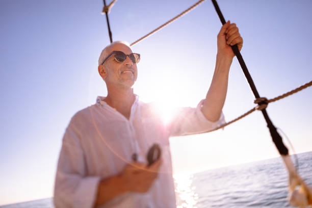 istock Smiling senior man on yacht sailing with compass in hand 520588368
