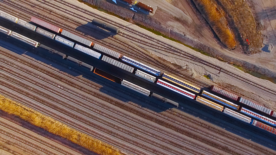 Many trains, train cars in rail yard on multiple railroad tracks in the early morning light. Aerial view.