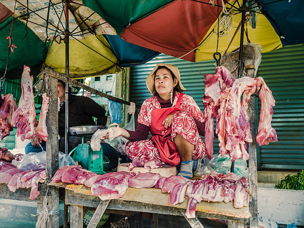 Siem Reap, Сambodia - February 25, 2016: People selling meat at Phsar Leu Thom Thmey market in Siem Reap Cambodia. This is one of the largest public markets of the city. Hundreds of market stalls inside the building and outside of it sell their goods everyday to local residents.