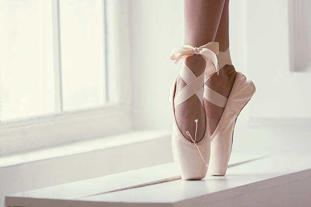 Legs of a ballerina in pointe Legs of a ballerina in pink pointe shoes with a bow are dancing near the window ballerina shoes stock pictures, royalty-free photos & images