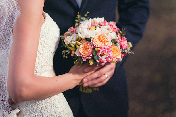 istock Hands of groom and bride on a wedding bouquet 520593752