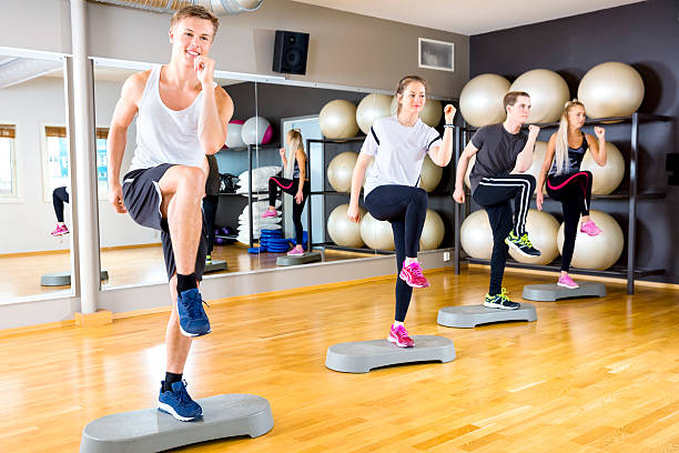 istock Smiling group raising legs on step platforms at fitness gym 520593774