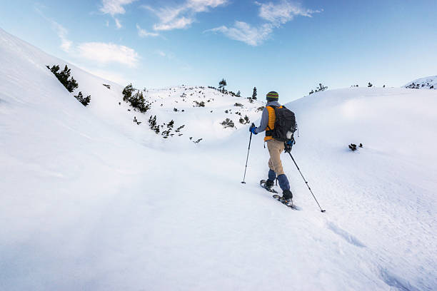 Seeking Peace and Quiet High in the Alps Man shoeshowing alone through a field of deep snow high in the Alps snow hiking stock pictures, royalty-free photos & images