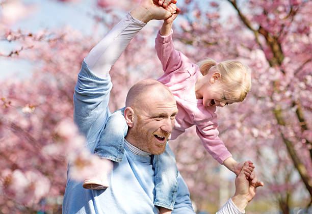 istock Father and daughter among cherry blossom trees 520594790