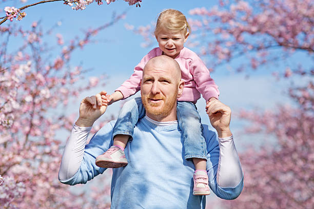 istock Father and daughter among cherry blossom trees 520594826