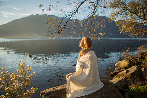 istock Woman sitting on rock with blanket watching sunrise 520598803