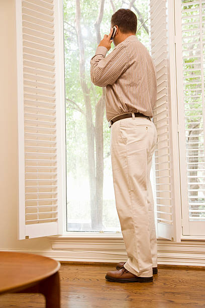 istock Man Standing in Front of Window on Cell Phone 520599381