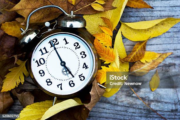 Retro Clock On A Wooden Table With Autumn Leaves Stock Photo - Download Image Now - Alarm Clock, Alertness, Antique