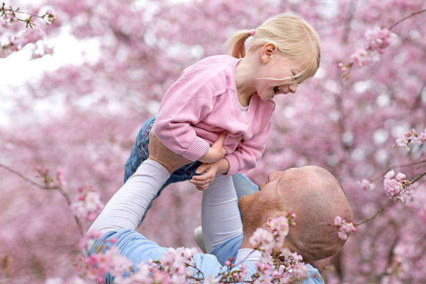 istock Father and daughter smiling among cherry blossom trees 520608098