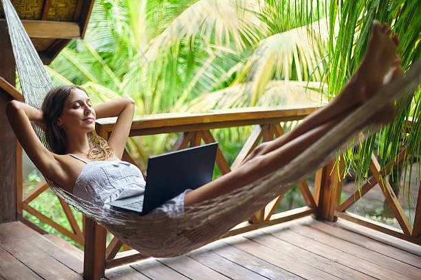 istock Young woman relaxing in a hammock with laptop 520608478