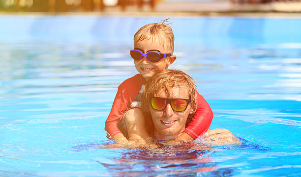 istock happy father and son swimmimng in the pool 520609358