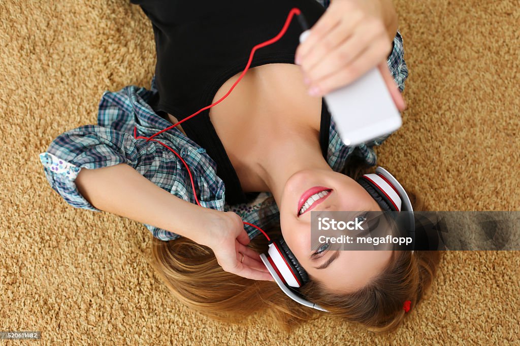 Hermosa rubia sonriente mujer tendido sobre piso alfombrado usa hea - Foto de stock de Equipo de música libre de derechos