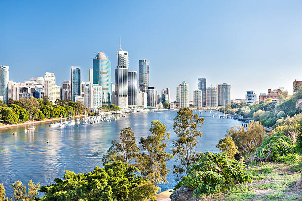 istock Blue water river surrounded by trees beside a modern city 520611914