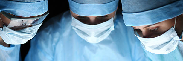 tre chirurghi al lavoro che operano in teatro chirurgica - medical accessories foto e immagini stock