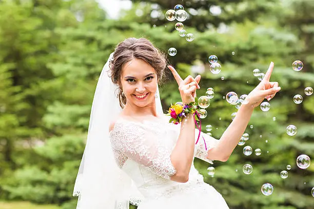 Young bride play with soap-bubble and joy smile.