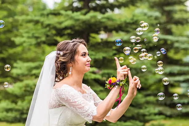 Young bride play with soap-bubble and joy smile.