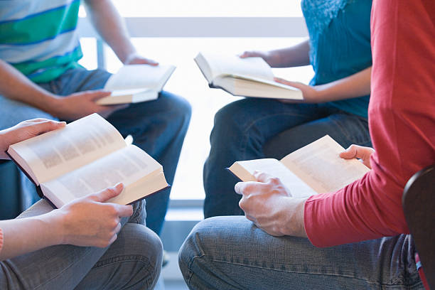 istock Four young people sitting in circle with books on laps 520620987