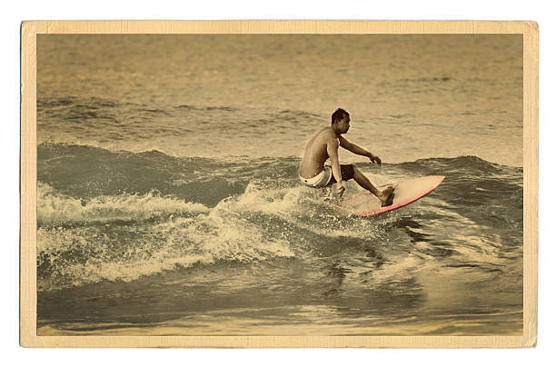 A Retro 40s-50s style antique postcard with a surfer surfing Pacific Ocean waves in the water off a tropical beach of Kauai, Hawaii, USA.