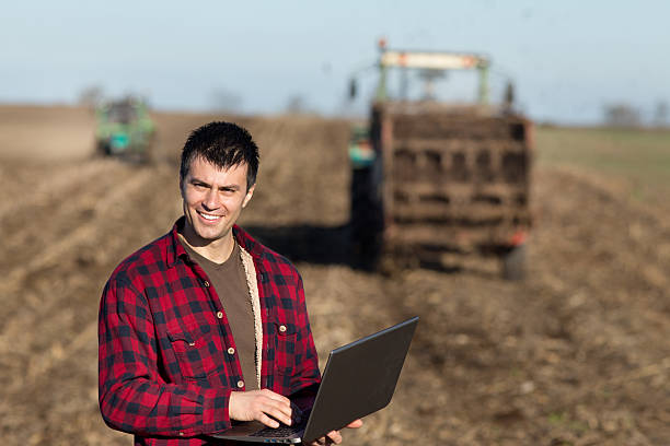 istock Farmer with laptop and tractors on field 520623514