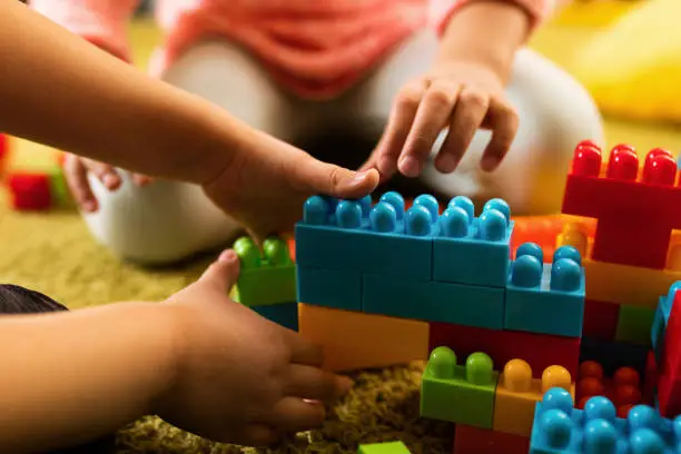 Photo of Close-up of two children playing with toy blocks.