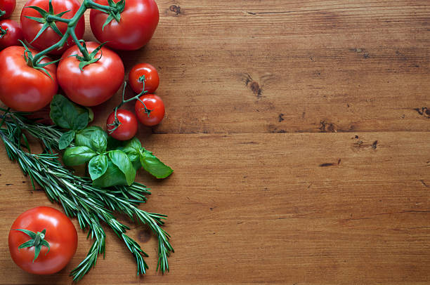 istock Tomatoes rosemary and basil on wooden background 520623895