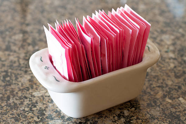 A stoneware container holding packets of artificial sweetener.