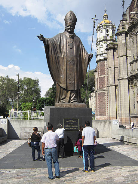 Mexico City, Mexico-October 9, 2014:  These tourists are admiring a statue of pope John Paul II at La Villa in Mexico City.  La Villa is a complex of churches and open square which draws tourist and worshipers.  John Paul II was the most popular of all the Catholic popes.