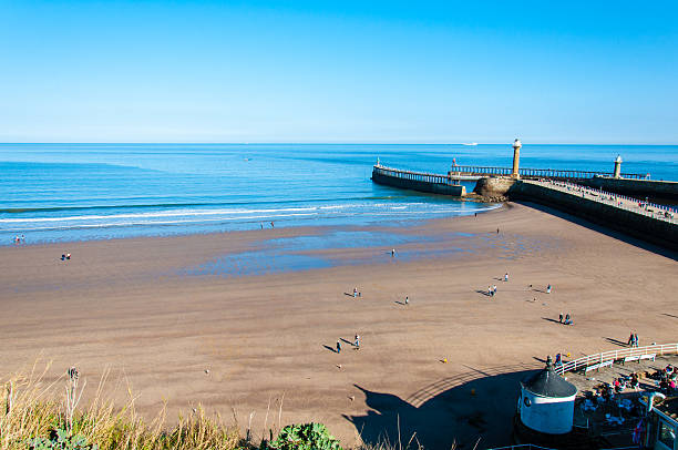 Whitby, North Yorkshire, UK - October 12, 2014: View of Whitby beach in a sunny autumn day.Whitby is a seaside town and port in North Yorkshire, UK. Its attraction as a tourist destination is enhanced by its association with the world famous horror novel Dracula, written by Bram Stoker.