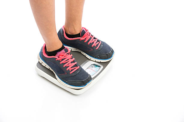 istock fitness young man's feet on weight scale 520646918