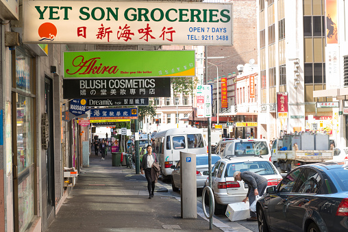 Sydney, Australia - November 6, 2015: A Young Asian woman walking along a row of shops in Sydney Chinatown.