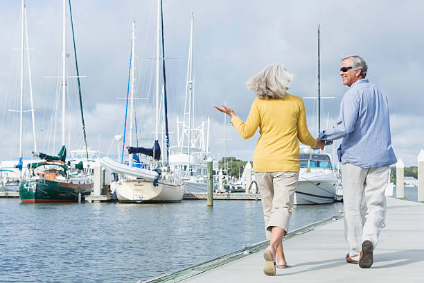 istock Happy senior couple walking along harbor holding hands 520655194