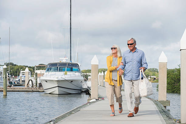 Happy senior couple walking along harbor holding hands