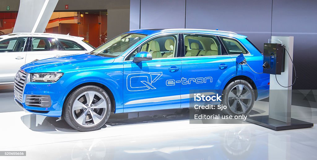 Audi Q7 e-tron plug-in hybrid SUV Brussels, Belgium - Januari 12, 2016: Blue Audi Q7 e-tron 3.0 TDI quattro plug-in hybrid SUV car next to an electric vehicle charging station. The Q7 e-tron plug-in hybrid is fitted with a V6 TDI engine combined with an electric motor and quattro drive. The car is on display during the 2016 Brussels Motor Show. The car is displayed on a motor show stand, with lights reflecting off of the body. Audi Stock Photo