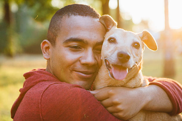 istock young man hug his small Mixed-breed dog, looking at camera 520658584