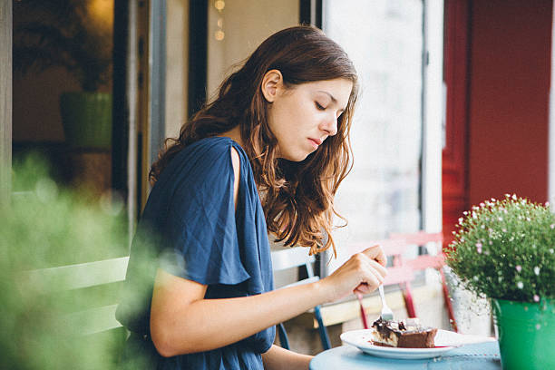istock young caucasian woman in sidewalk cafe eats a cake 520659044