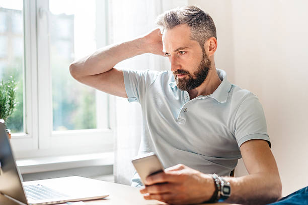 istock young bearded business man with smartphone looking at laptop 520659632