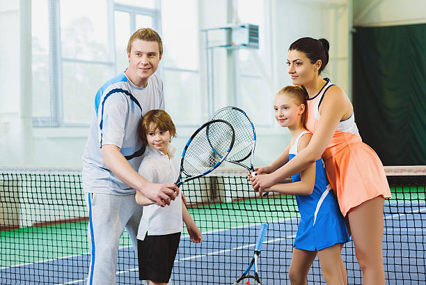 Young woman and man or coach teaching children how to stock photo