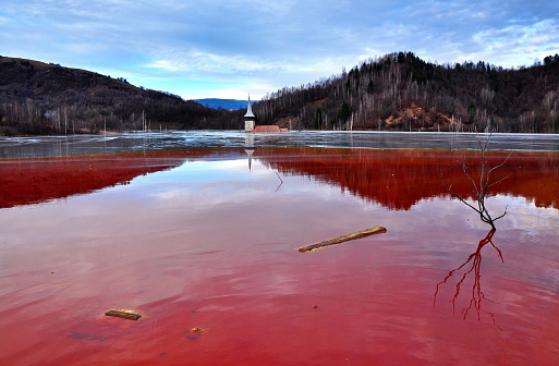 Flooded church in a toxic red lake. Water polluting by a copper mine