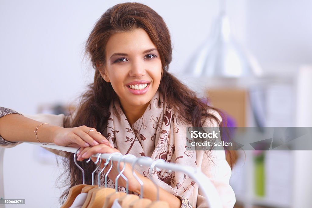 Beautiful young stylist near rack with hangers Beautiful young stylist near rack with hangers, isolated Adult Stock Photo